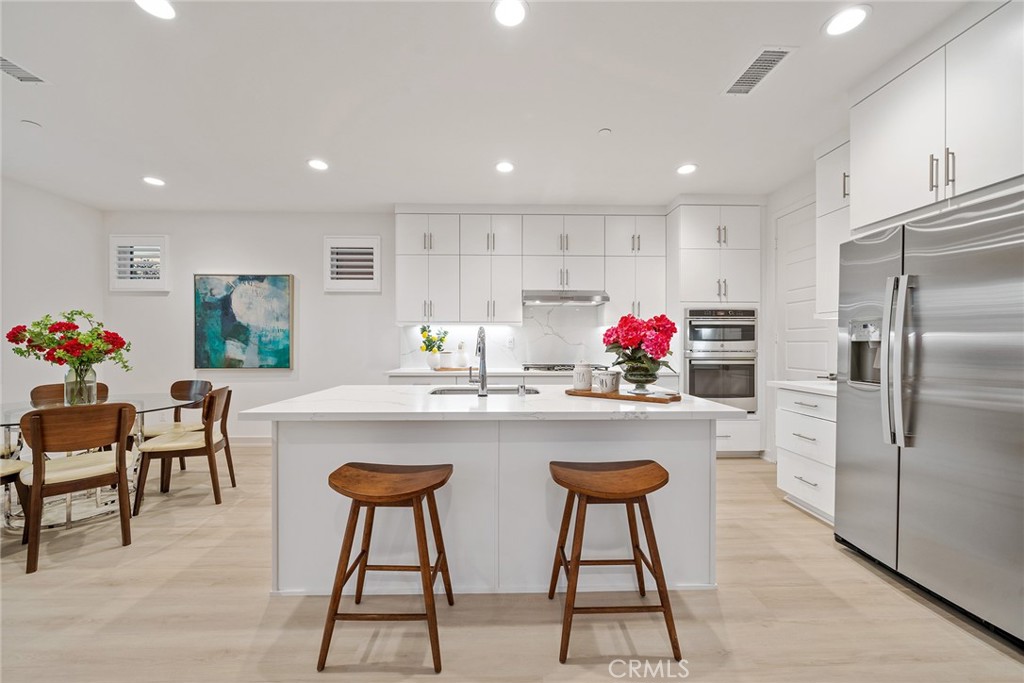 131 Restore Irvine, CA 92618 - Photo 6 of 43 a kitchen with stainless steel appliances granite countertop a dining table chairs and white cabinets