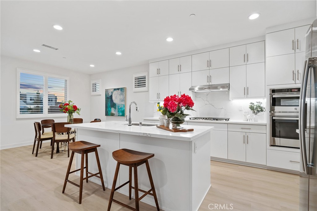 131 Restore Irvine, CA 92618 - Photo 9 of 43 a kitchen with stainless steel appliances kitchen island granite countertop a dining table chairs and white cabinets