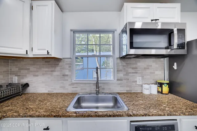 a kitchen with granite countertop a sink and a stove