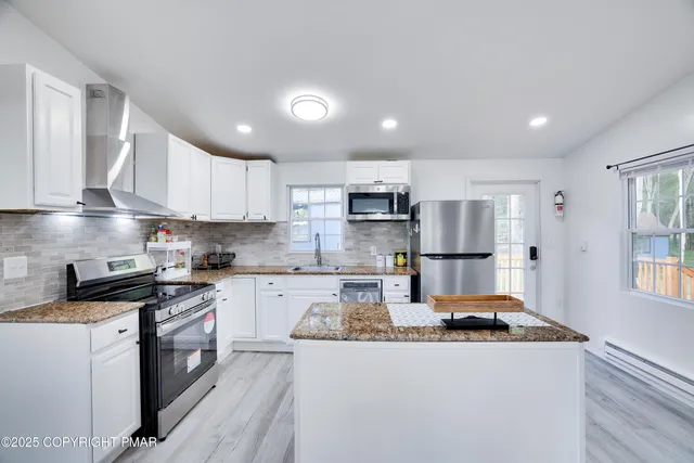 a kitchen with stainless steel appliances granite countertop a stove a sink a refrigerator and white cabinets