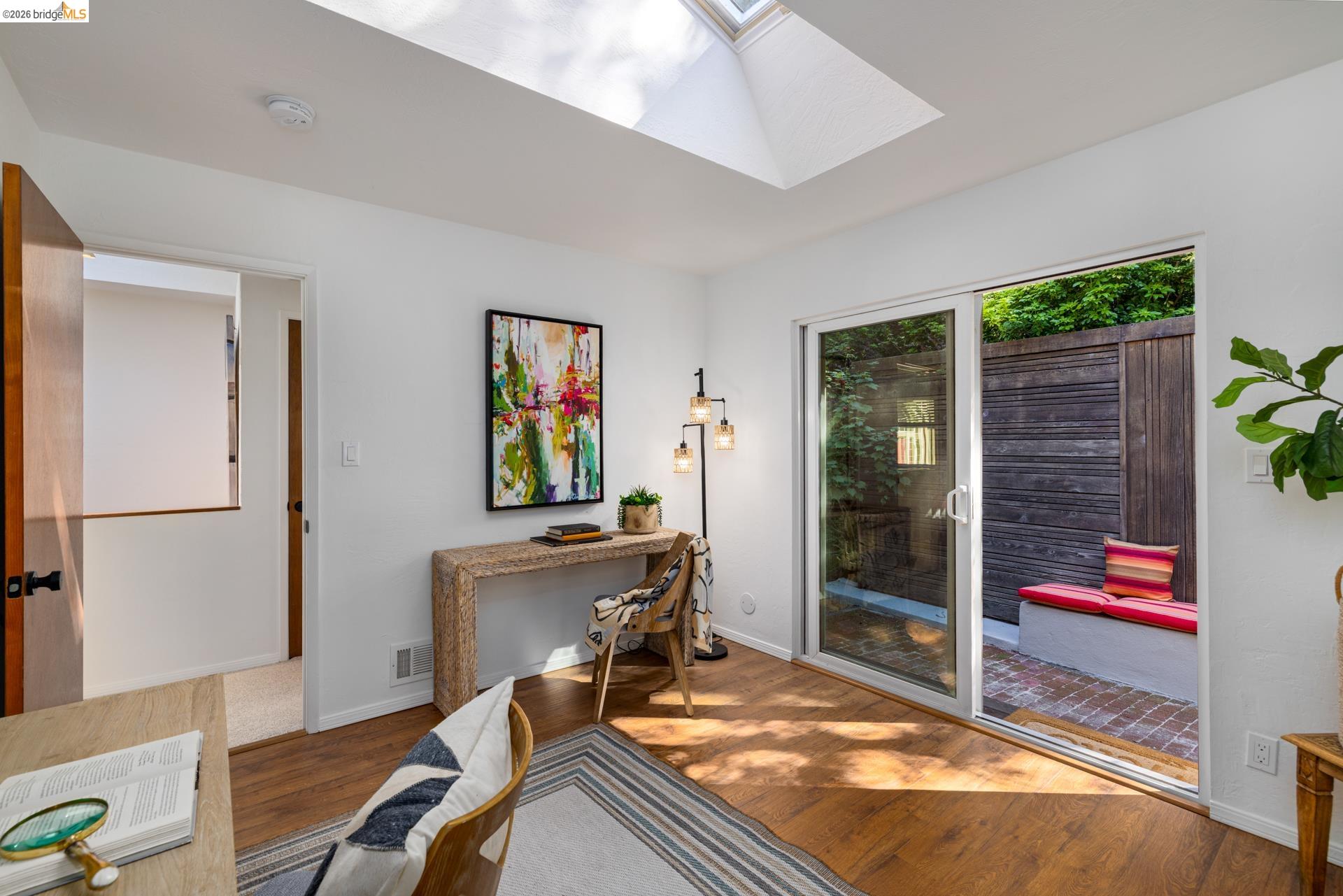 6660 Sobrante Road Oakland, CA 94611 - Photo 32 of 48 Wood-finish flooring, skylight, and sliding glass doors to a private outdoor space with a built-in bench and wood fencing