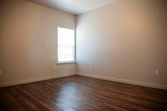 an empty room with wooden floor closet and windows