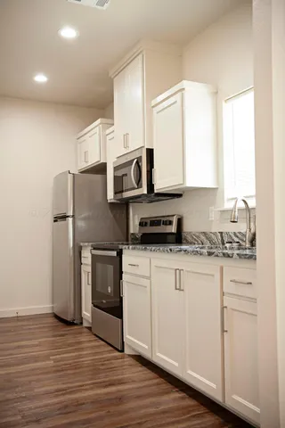 a view of a kitchen with a sink refrigerator and wooden floor