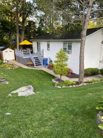 a backyard of a house with table and chairs and a large tree