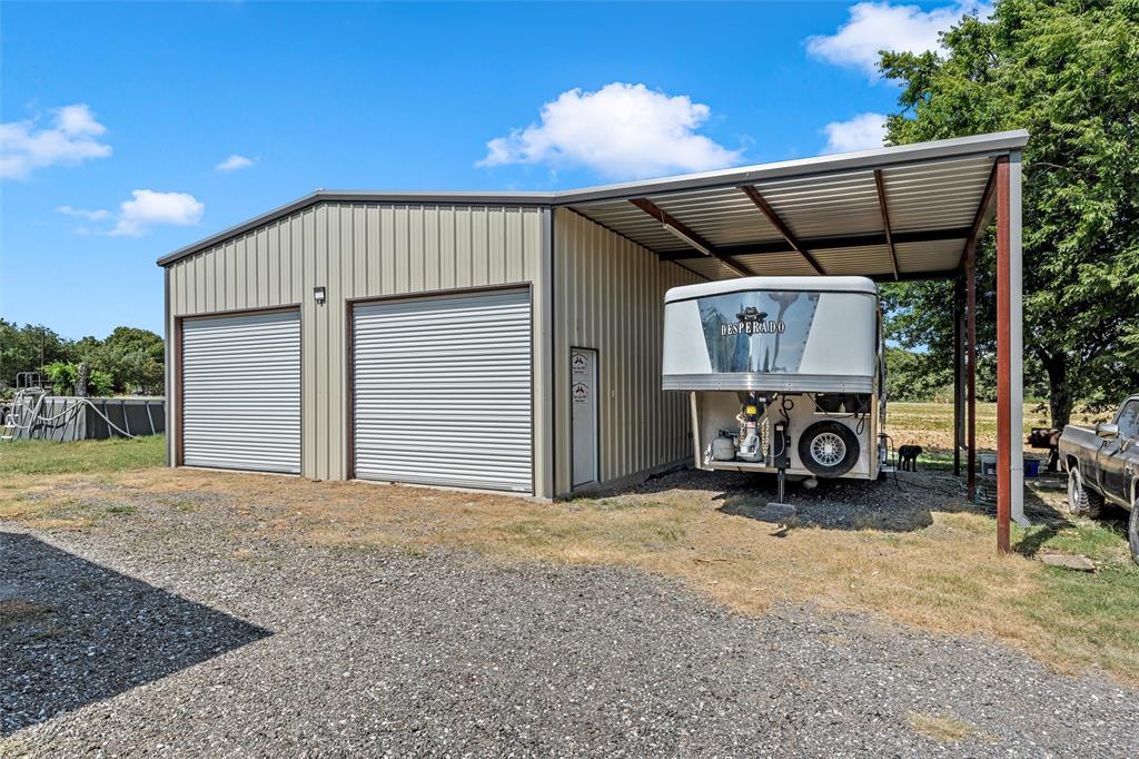 602 3rd Street Abbott, TX 76621 - Photo 28 of 40 Metal-sided structure featuring two roll-up doors, exterior lighting, and an attached covered carport