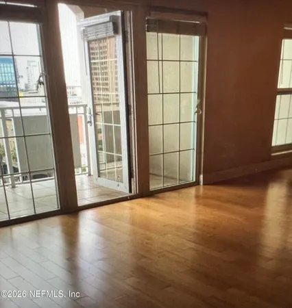 an empty room with wooden floor and windows