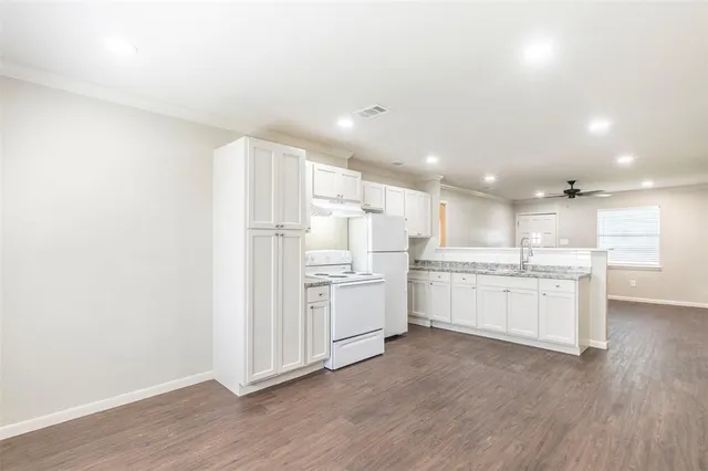 a view of an empty room with wooden floor and a sink