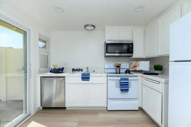 a kitchen with white cabinets and white appliances