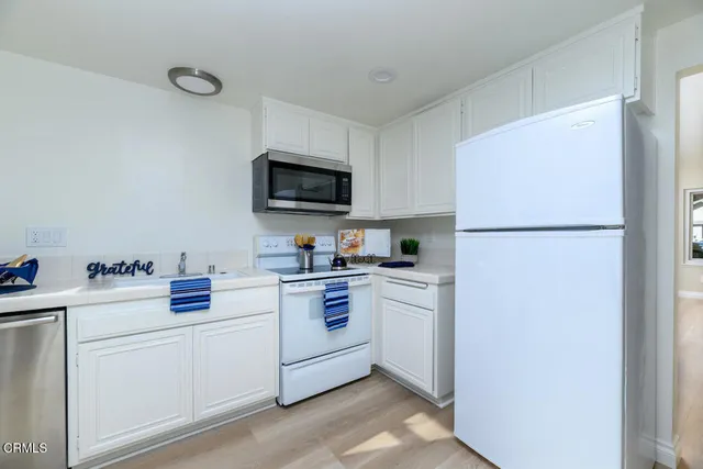 a kitchen with white cabinets and white appliances