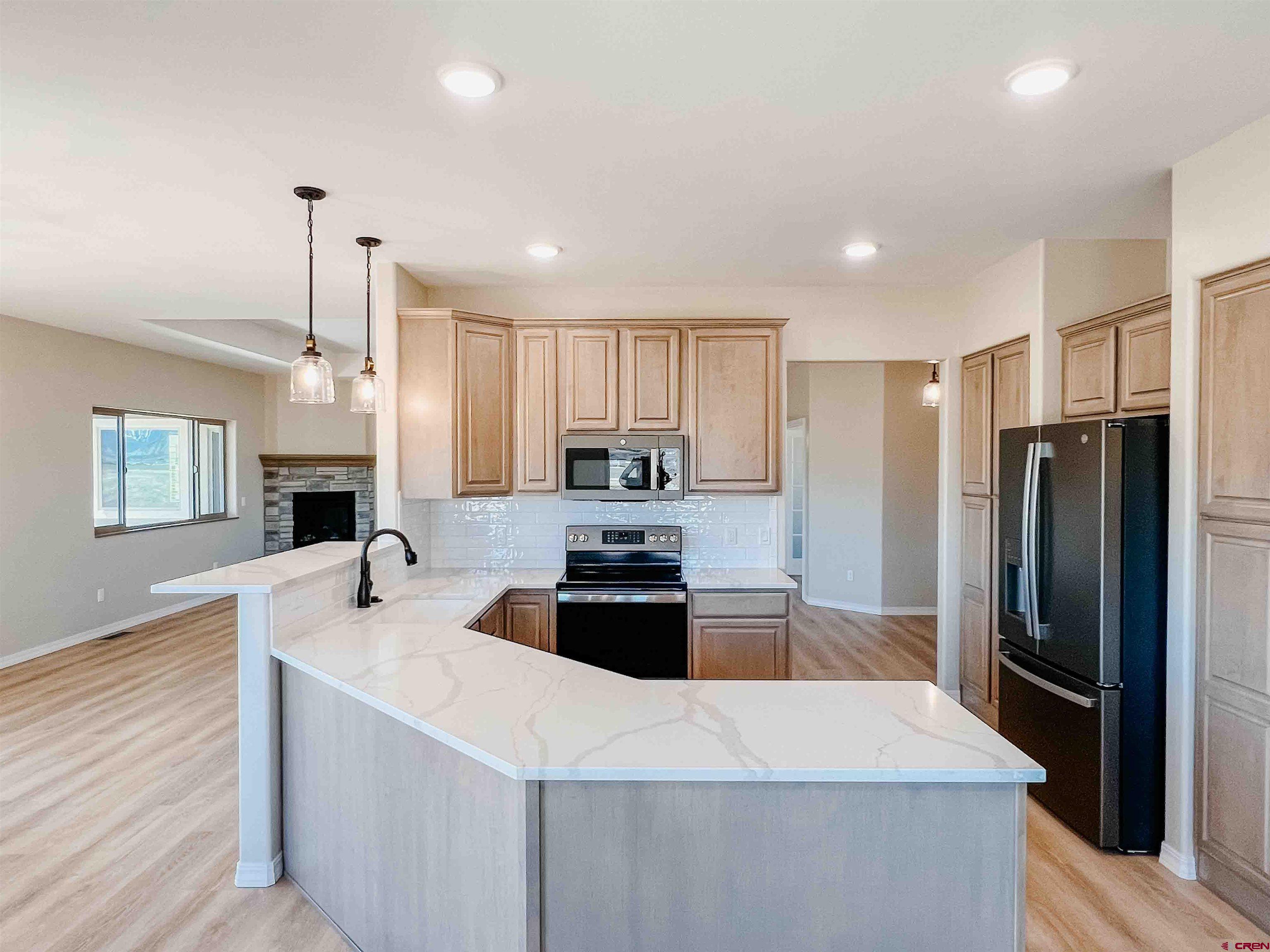 68364 Vernal Road Montrose, CO 81403 - Photo 2 of 11 a kitchen with a refrigerator a stove a sink and a center island