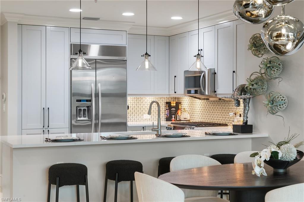 9115 Strada Place, Unit 5406 Naples, FL 34108 - Photo 15 of 50 a kitchen with granite countertop a table chairs stove and refrigerator