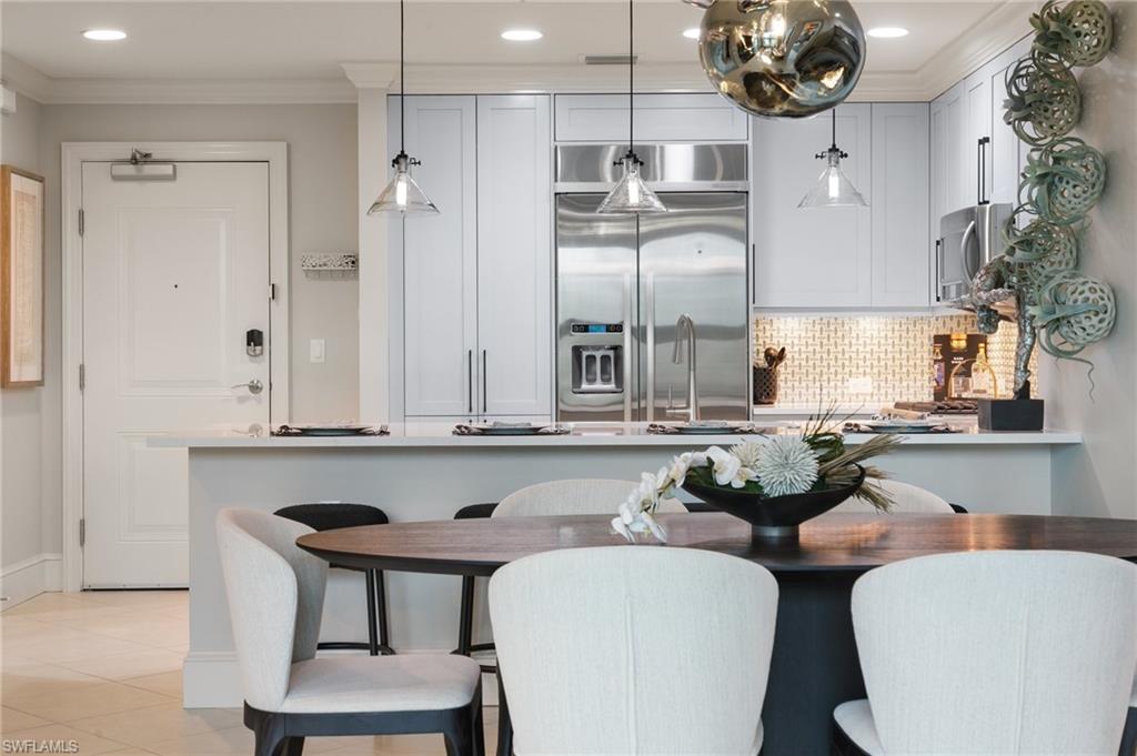 9115 Strada Place, Unit 5406 Naples, FL 34108 - Photo 16 of 50 a kitchen with a table chairs stove and cabinets