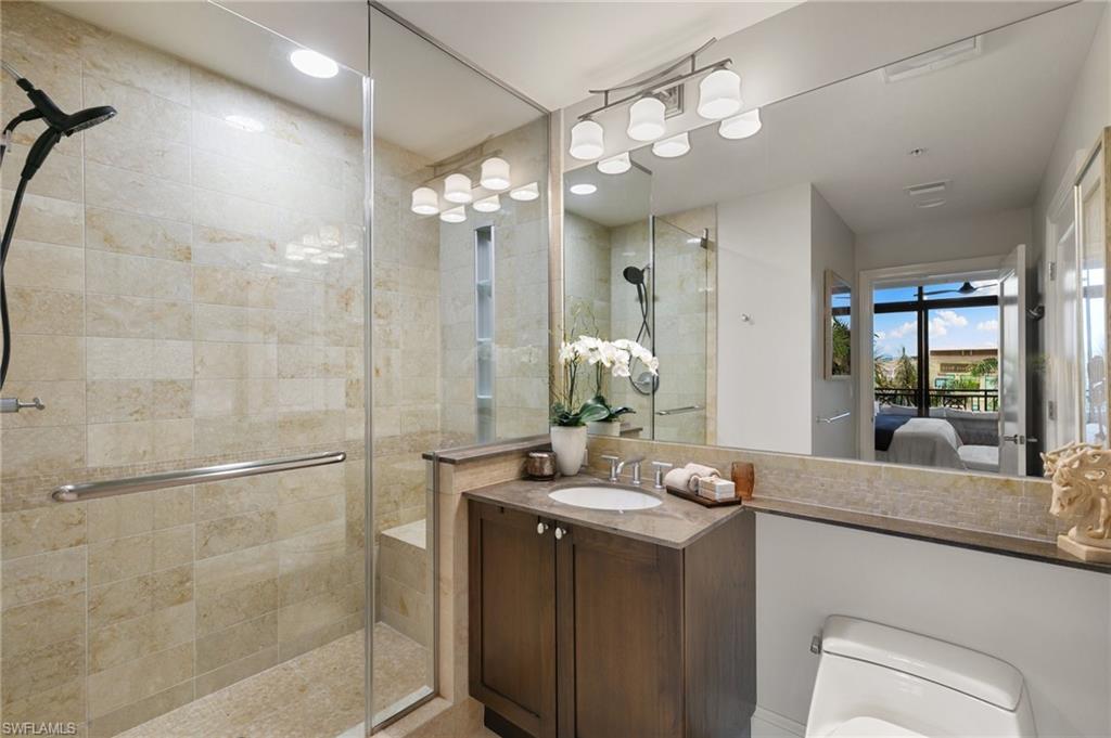 9115 Strada Place, Unit 5406 Naples, FL 34108 - Photo 27 of 50 a bathroom with a granite countertop sink a large mirror and shower