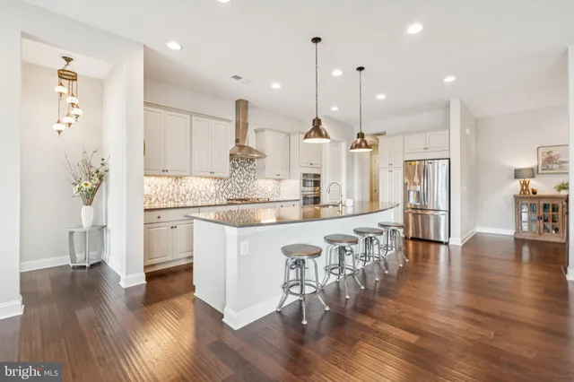 a kitchen with stainless steel appliances granite countertop a table chairs stove and wooden floor