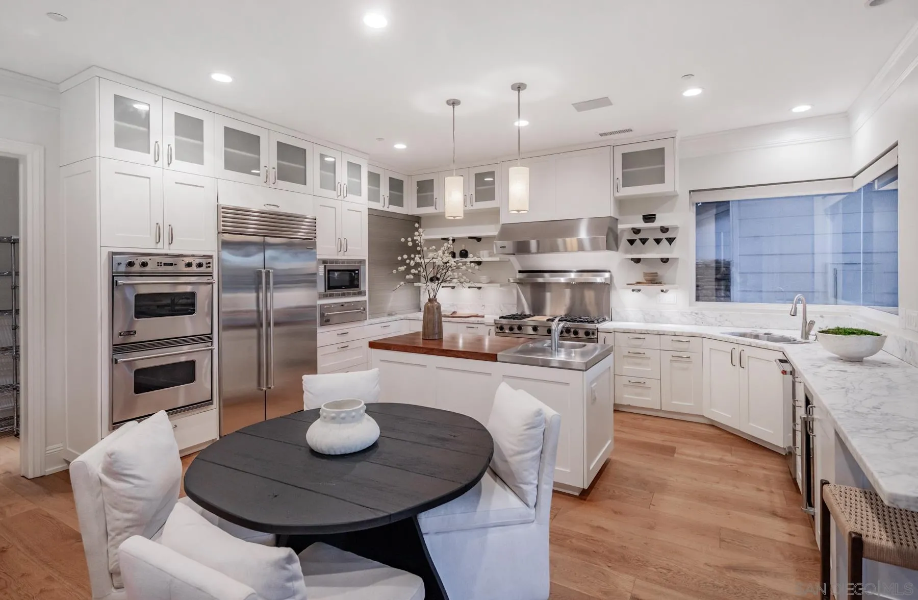 1650 Bella Laguna Court Encinitas, CA 92024 - Photo 14 of 41 a kitchen with stainless steel appliances kitchen island granite countertop a sink a stove a refrigerator and a dining table with wooden floor