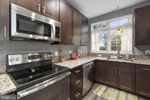a kitchen with stainless steel appliances a sink a stove a microwave cabinets and a window