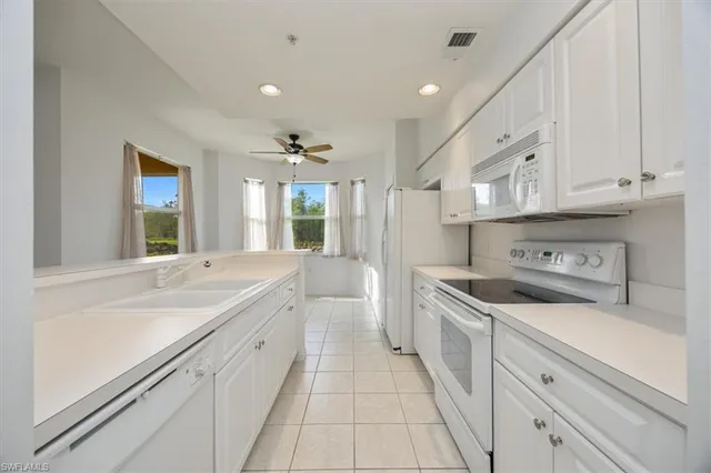 a large white kitchen with stainless steel appliances granite countertop a sink and dishwasher a stove with white cabinets