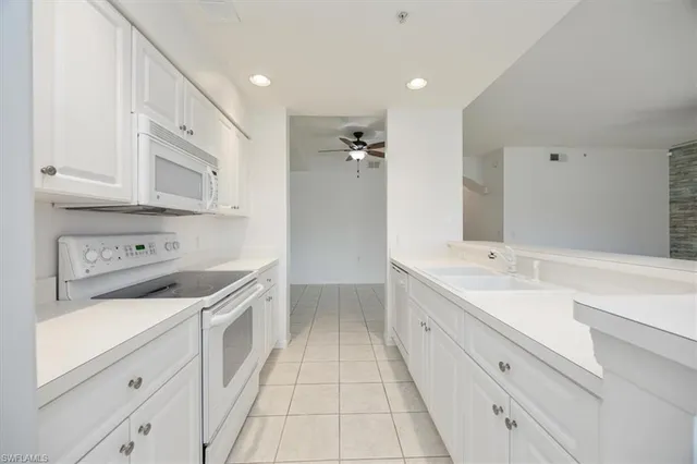 a kitchen with a sink dishwasher stove and white cabinets