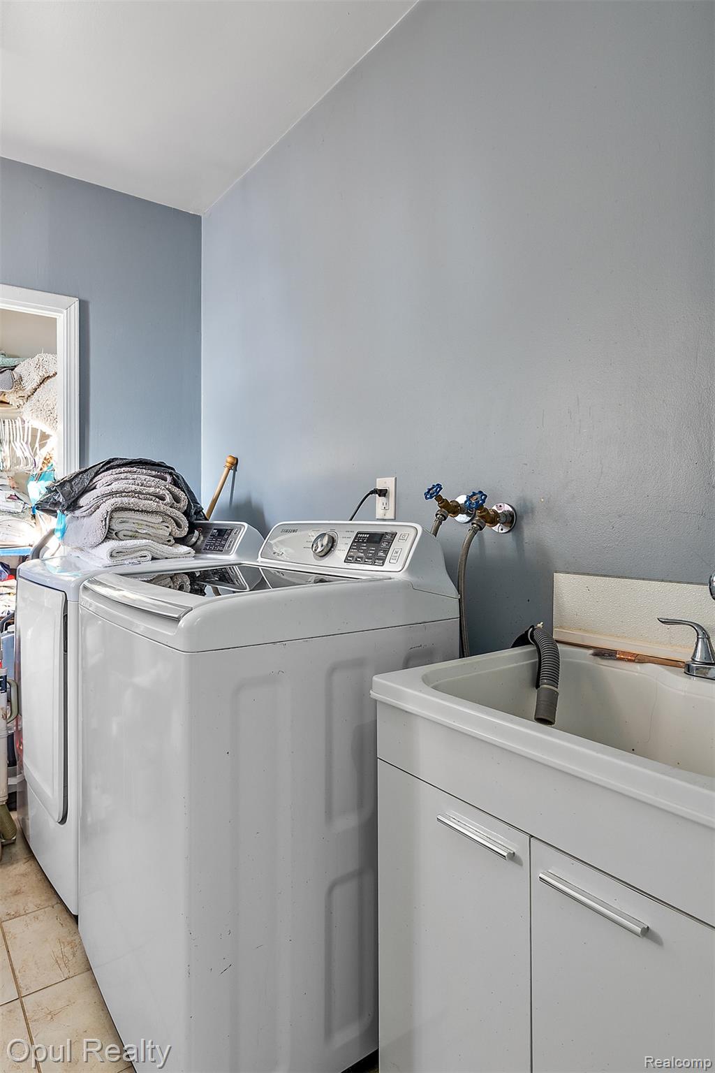 8855 Gross Road Dexter, MI 48130 - Photo 30 of 45 Dedicated laundry area featuring a utility sink with a white cabinet base, wall-mounted water hookups, and ceramic tile flooring