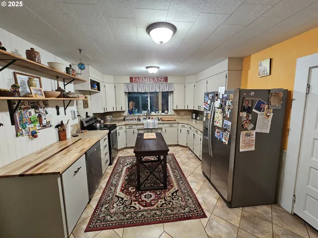 a kitchen with stainless steel appliances granite countertop a refrigerator a stove and a sink