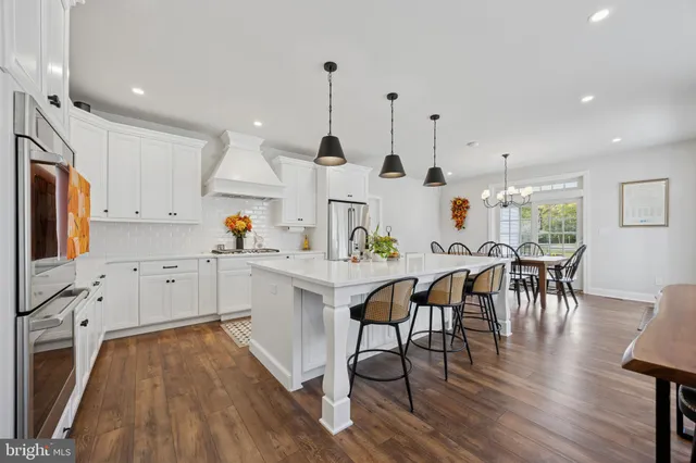 a kitchen with stainless steel appliances granite countertop a sink a microwave a refrigerator and chairs