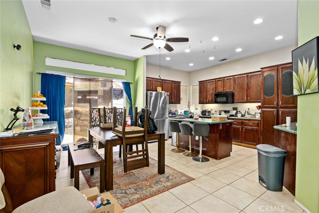 410 Windfields Way Beaumont, CA 92223 - Photo 5 of 41 a open kitchen with stainless steel appliances kitchen island granite countertop a table chairs and a refrigerator