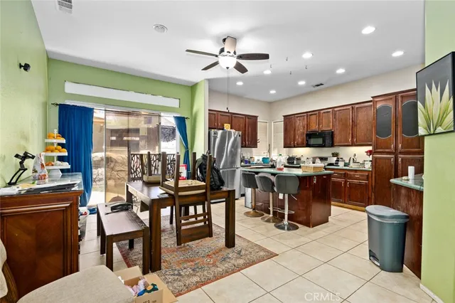 a open kitchen with stainless steel appliances kitchen island granite countertop a table chairs and a refrigerator