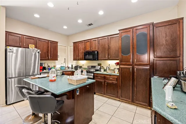 a kitchen with stainless steel appliances granite countertop a refrigerator a sink a stove a dining table and chairs