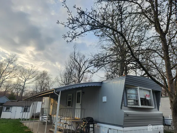 a front view of a house with yard and trees in the background