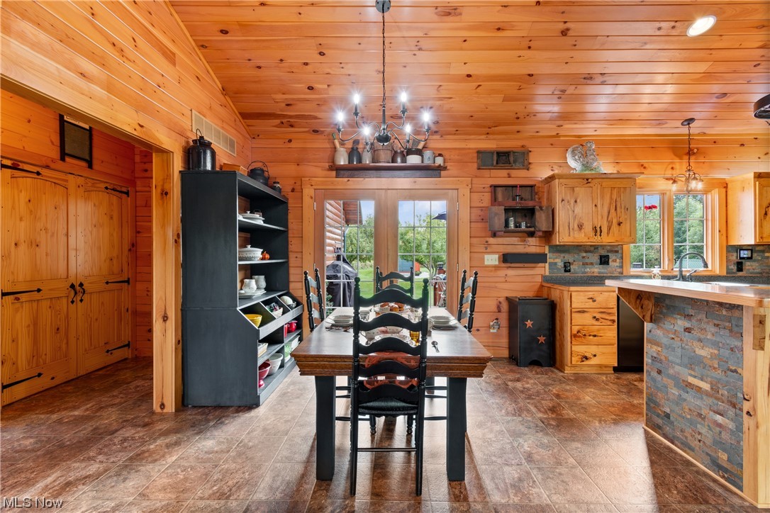 8205 Lake Road Seville, OH 44273 - Photo 14 of 35 Dining space with a notable chandelier, vinyl tile floors, wooden walls, wooden ceiling, a wealth of natural light, and vaulted ceiling