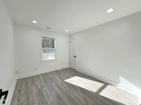 an empty room with wooden floor and windows
