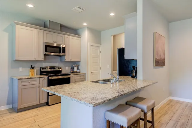 a kitchen with kitchen island granite countertop a stove top oven a sink a counter space and cabinets