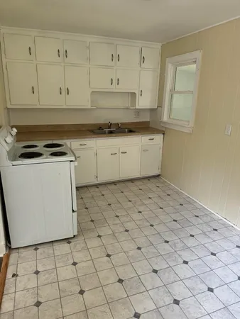 a kitchen with a stove a white cabinet and a granite counter tops