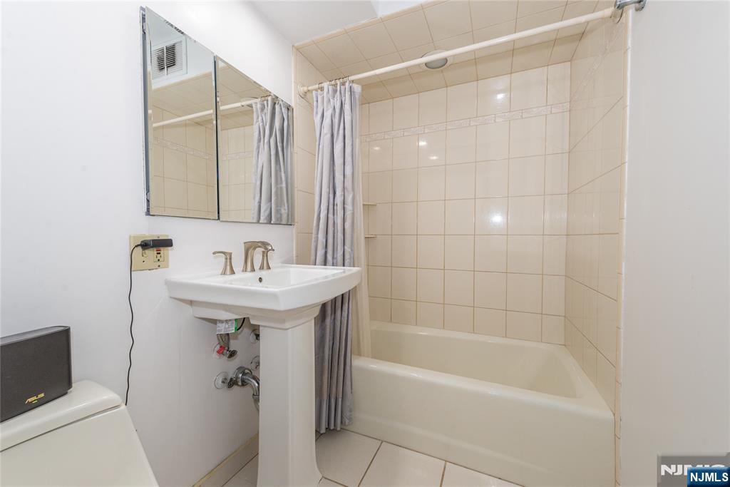90 Prospect Avenue, Unit 10A Hackensack, NJ 07601 - Photo 23 of 35 a bathroom with a shower a sink and mirror