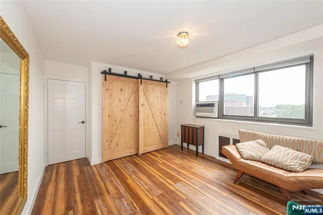 a bedroom with a bed a dresser a chandelier and a window