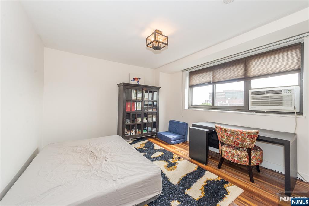 90 Prospect Avenue, Unit 10A Hackensack, NJ 07601 - Photo 27 of 35 a bedroom with a bed a dresser a chandelier and a window