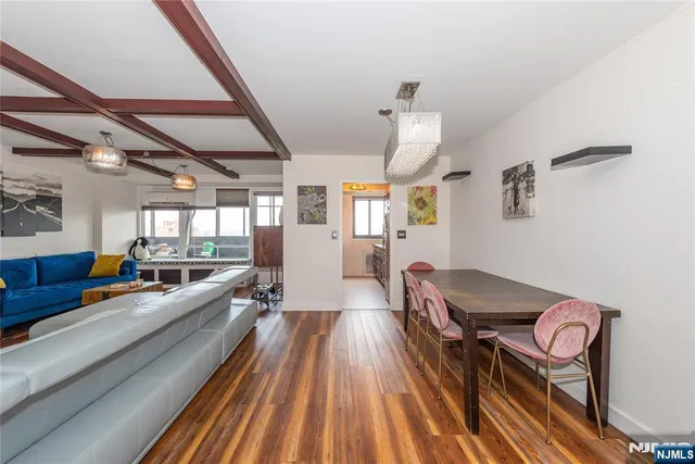 a living room with stainless steel appliances furniture a rug and a hard wood floor