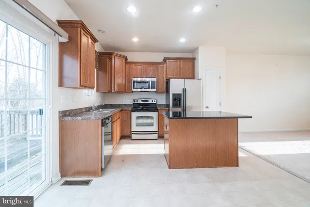 a kitchen with stainless steel appliances granite countertop a stove top oven a sink and a refrigerator