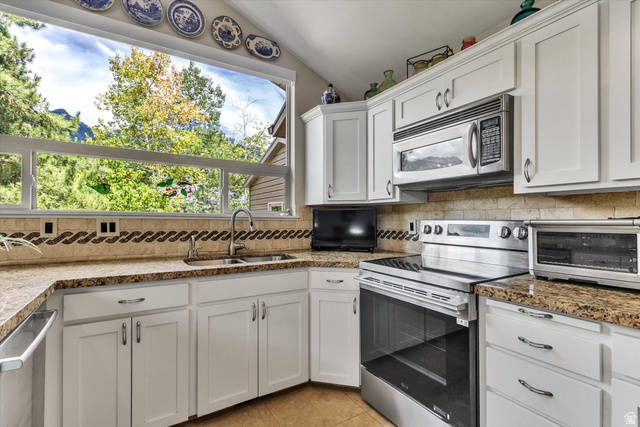 2863 Fallentine Road Sandy, UT 84093 - Photo 14 of 48 Kitchen featuring a large window, white cabinetry, granite countertops, and stainless steel appliances