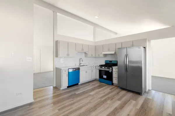 a kitchen with stainless steel appliances granite countertop a stove a refrigerator and a sink with wooden floor