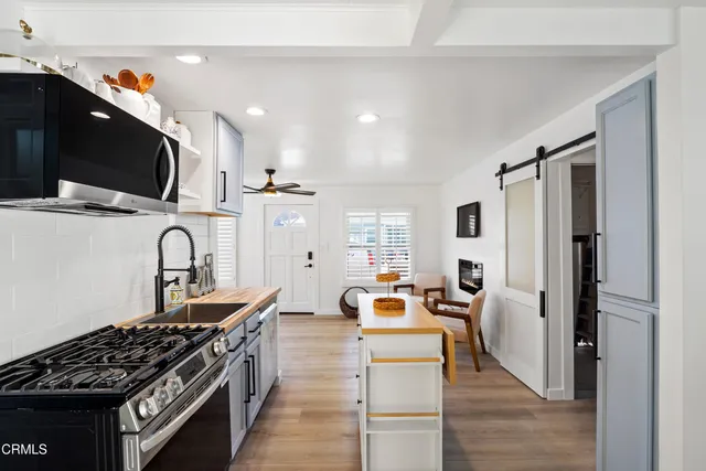 a kitchen with stainless steel appliances granite countertop a stove top oven a sink dishwasher and a refrigerator with wooden floor