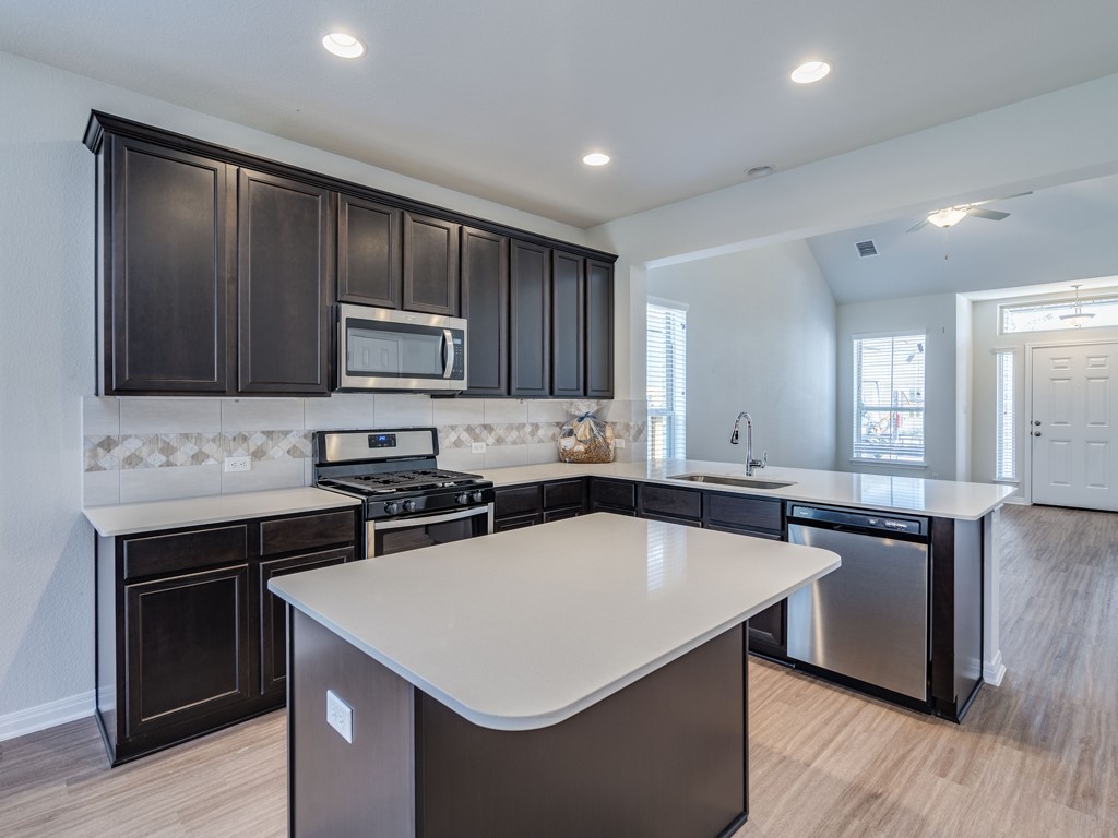 4113 Birdwatch Loop, Unit 21 Pflugerville, TX 78660 - Photo 6 of 30 a kitchen with a stove a sink and a microwave