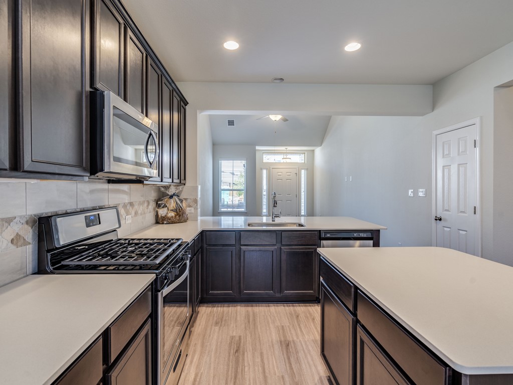 4113 Birdwatch Loop, Unit 21 Pflugerville, TX 78660 - Photo 7 of 30 a kitchen with stainless steel appliances a sink stove and cabinets