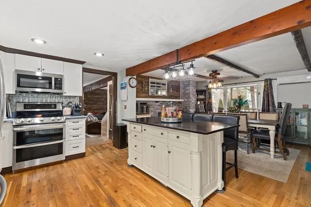 a kitchen with stainless steel appliances kitchen island granite countertop a table chairs in it and wooden floors