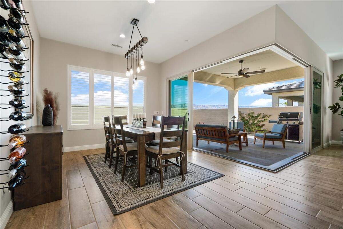 24 Claret Road Rancho Mirage, CA 92270 - Photo 12 of 34 a dining room with wooden floor a chandelier a wooden table and chairs