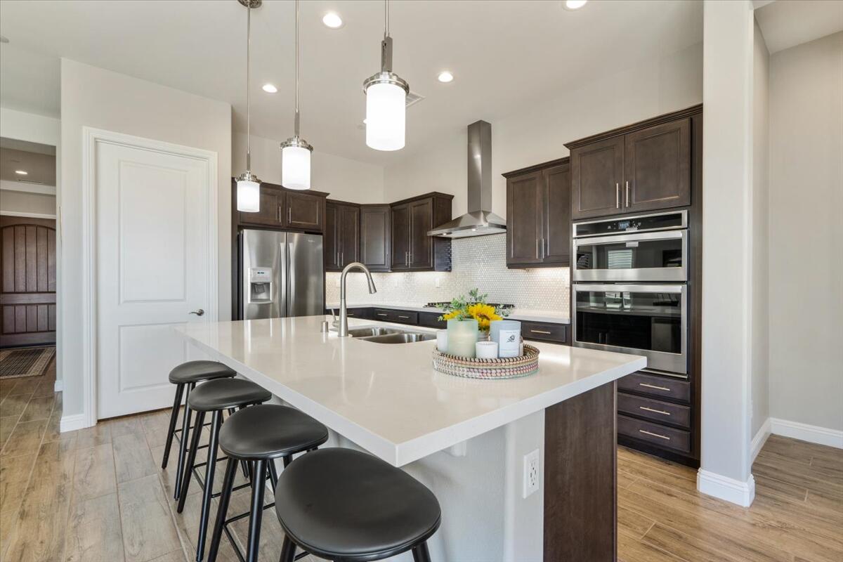 24 Claret Road Rancho Mirage, CA 92270 - Photo 8 of 34 a kitchen with a sink a stove and chairs with wooden floor