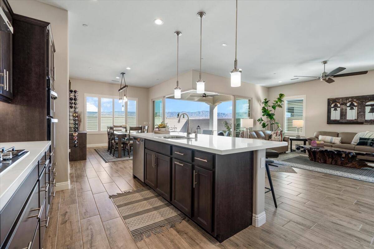 24 Claret Road Rancho Mirage, CA 92270 - Photo 10 of 34 a large kitchen with stainless steel appliances granite countertop a stove a sink dishwasher a living room with wooden floor and cabinets