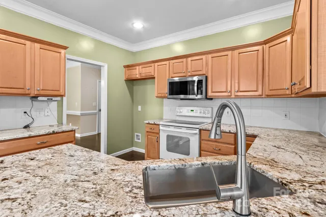 a kitchen with stainless steel appliances kitchen island granite countertop a sink stove and refrigerator