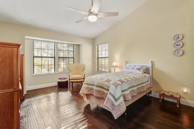 a bedroom with a bed wooden floor and windows