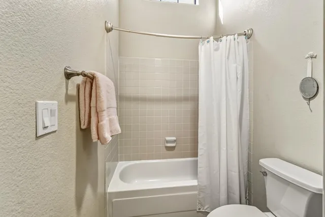 a bathroom with a shower a toilet and bathtub